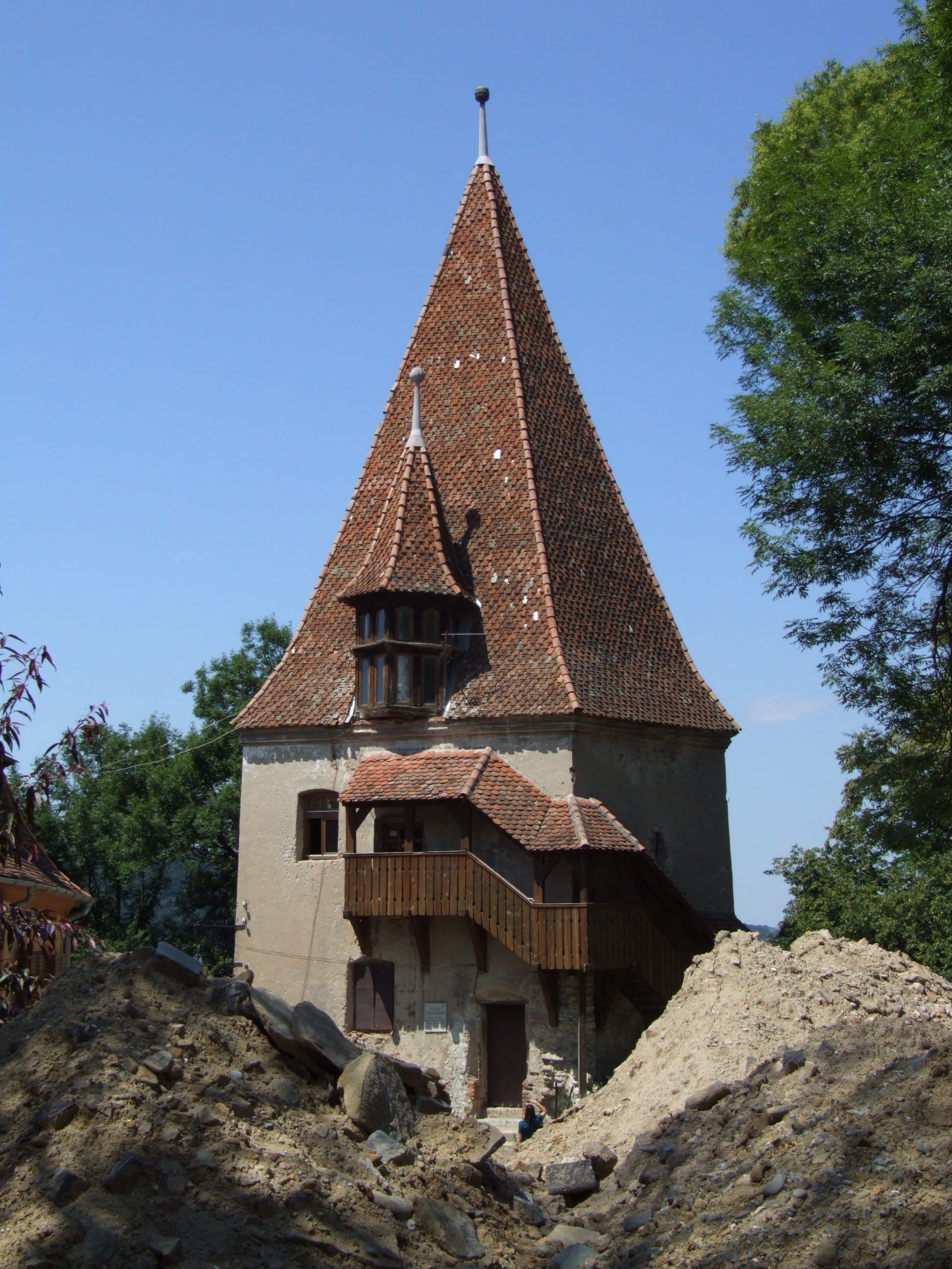 A colourful medieval clock tower and fortified buildings on a hillside