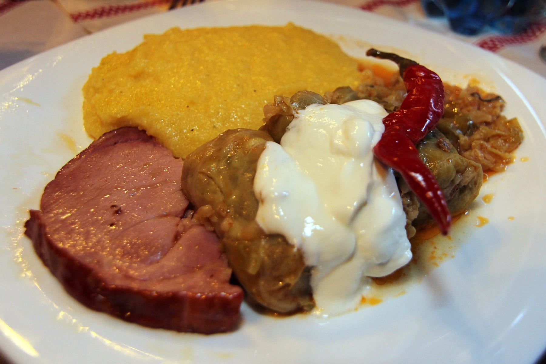 Cabbage rolls served with polenta, sour cream and hot peppers