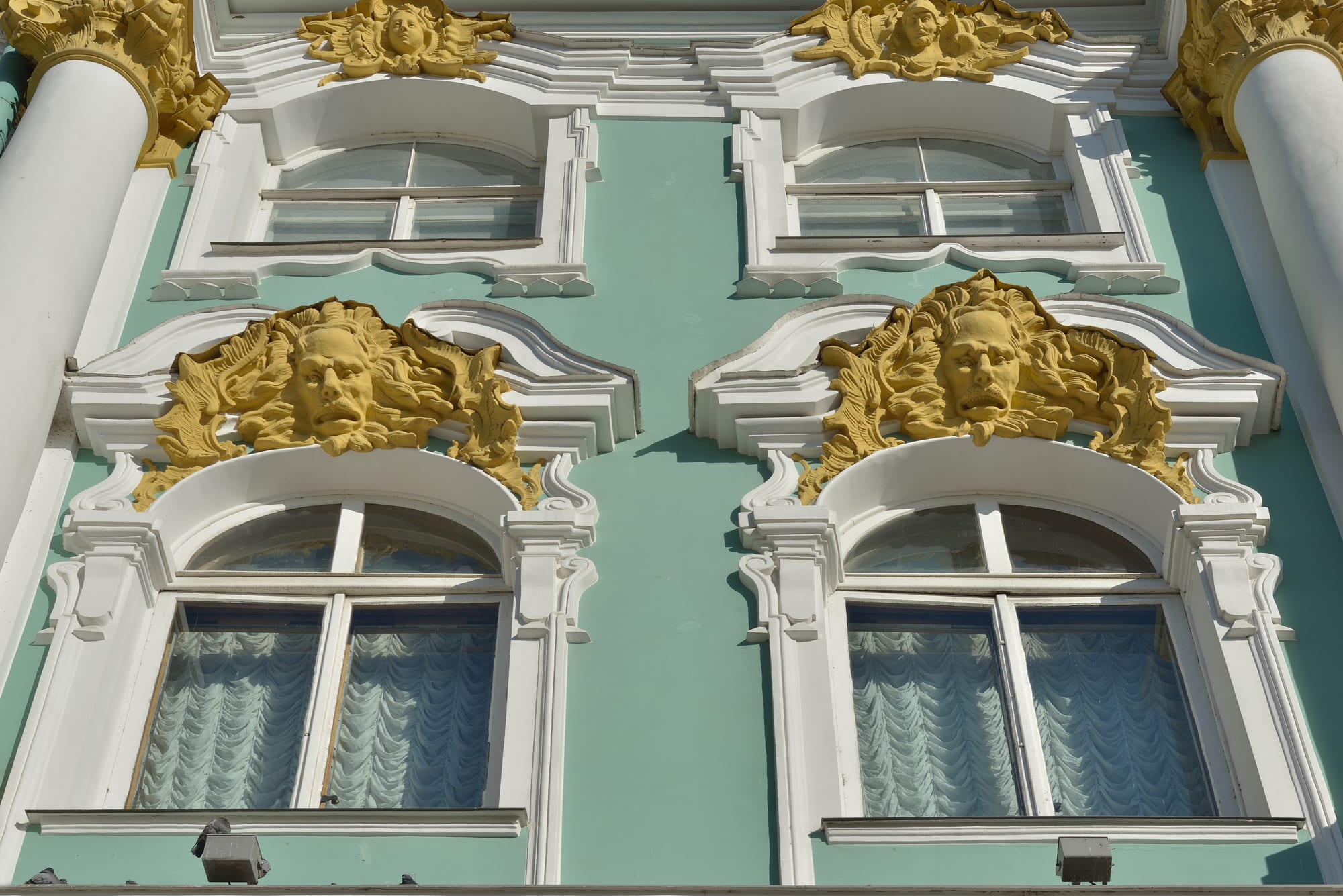 An ornate green and white baroque palace facade with gold detailing