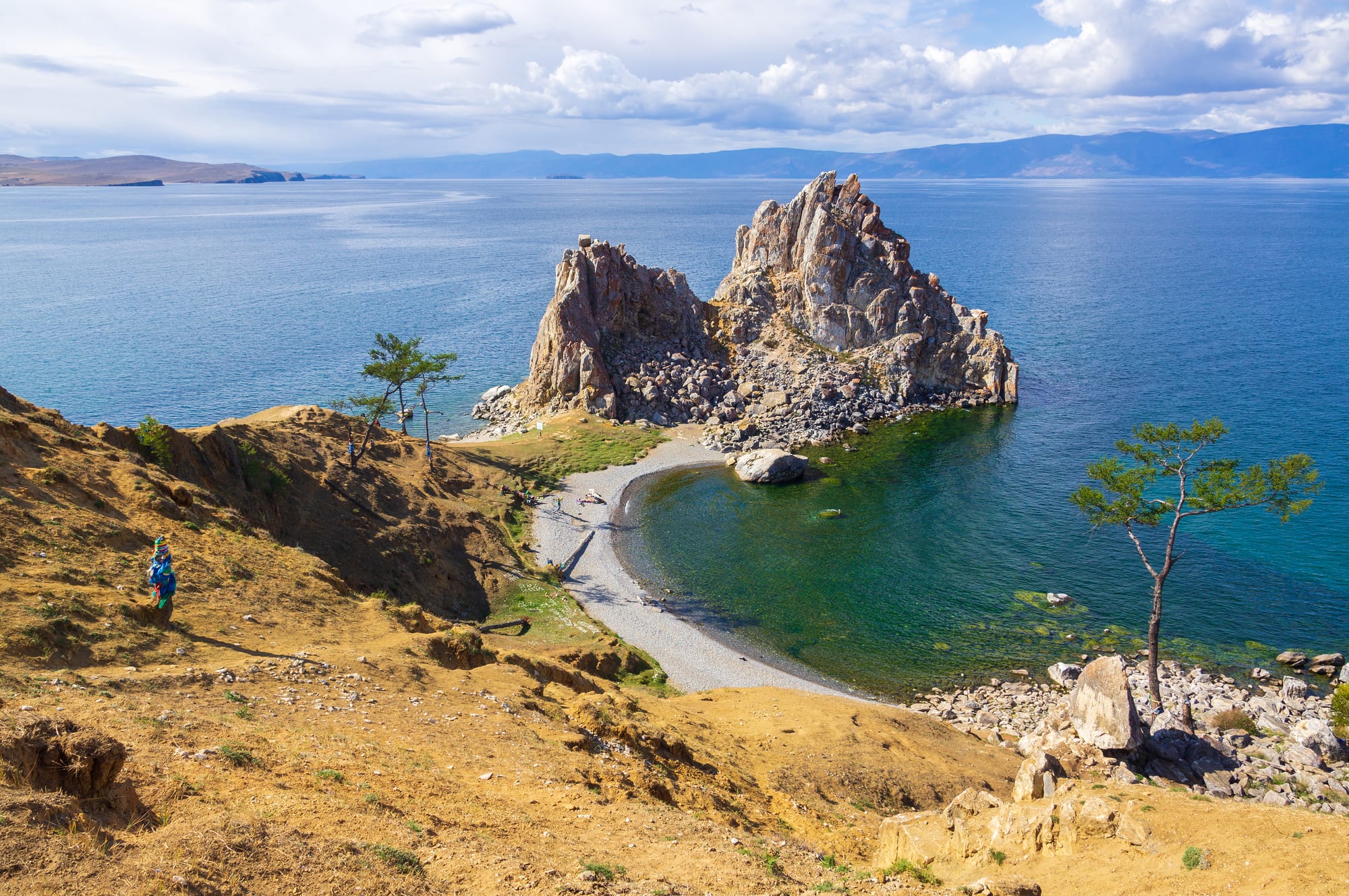 A rocky headland jutting into a vast, clear blue lake