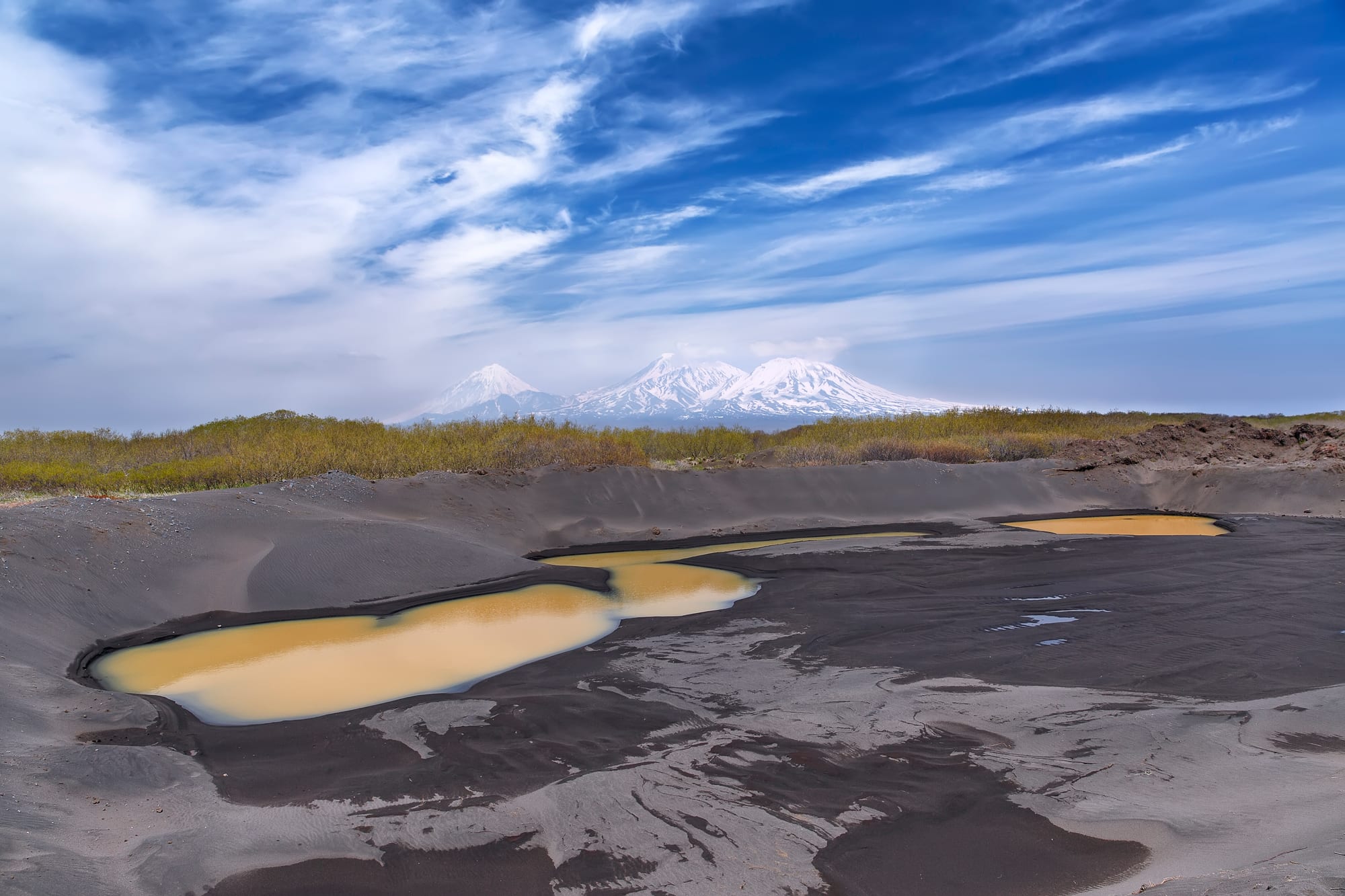 A row of snow-capped volcanic peaks rising above a remote landscape