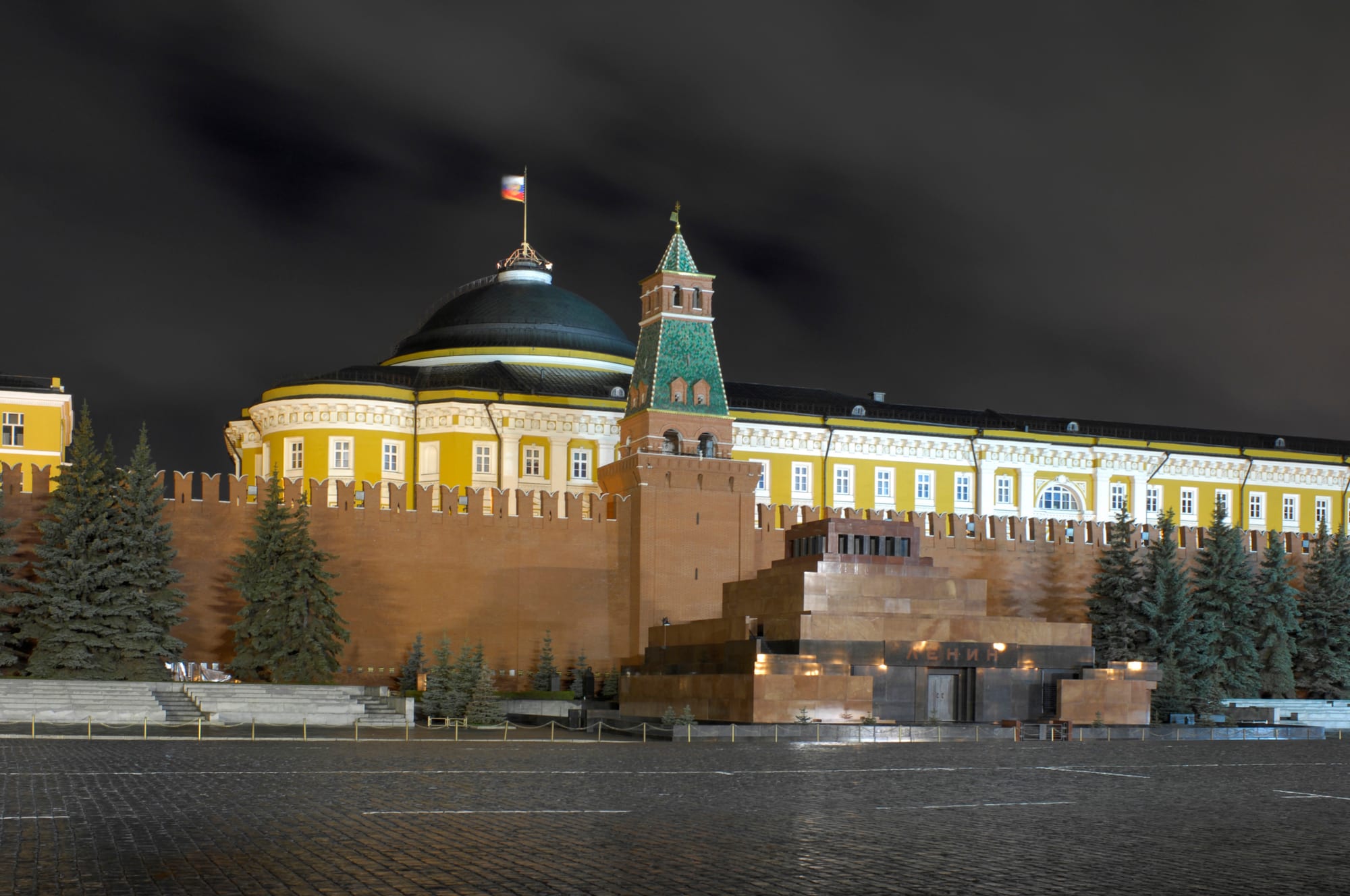 The floodlit red brick walls and towers of the Moscow Kremlin reflected in water at night