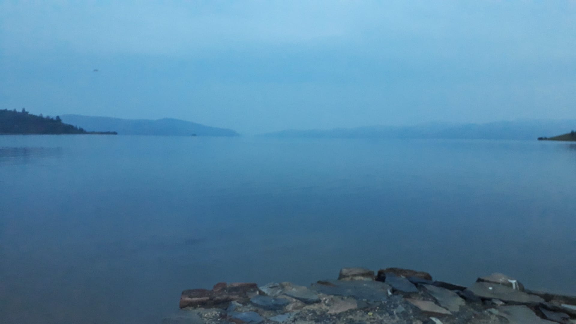 A calm lake with hills in the background at sunrise