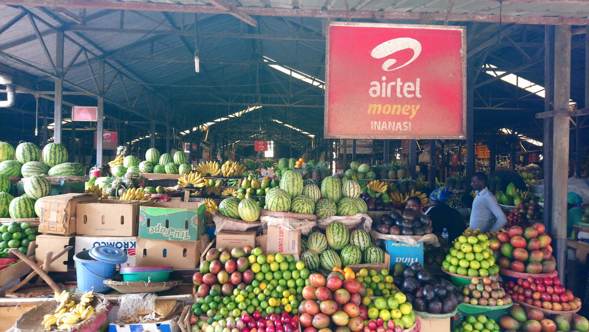 Stacks of watermelons, bananas, avocados and tomatoes at a busy market