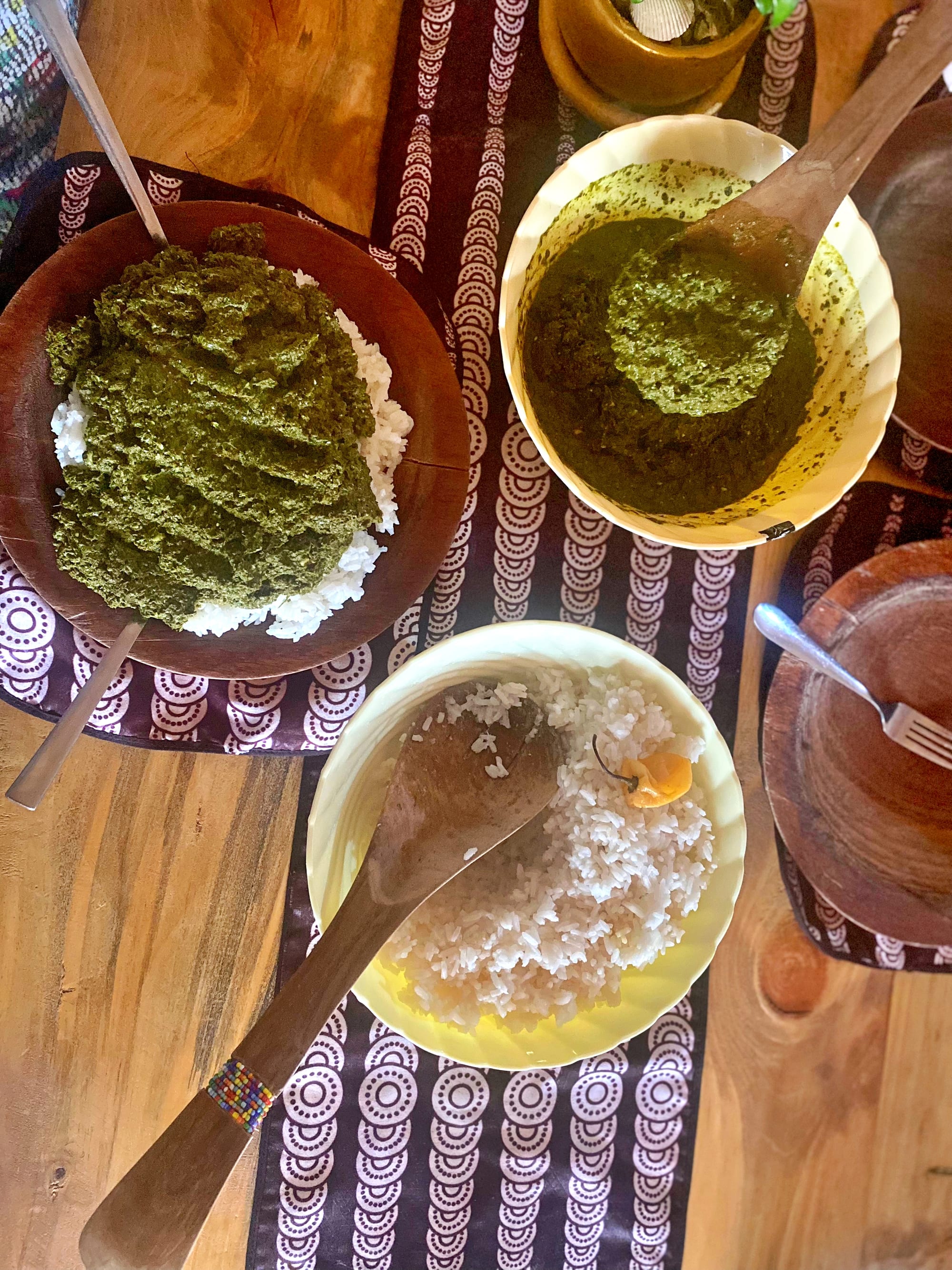 Bowls of cooked cassava leaves served with rice