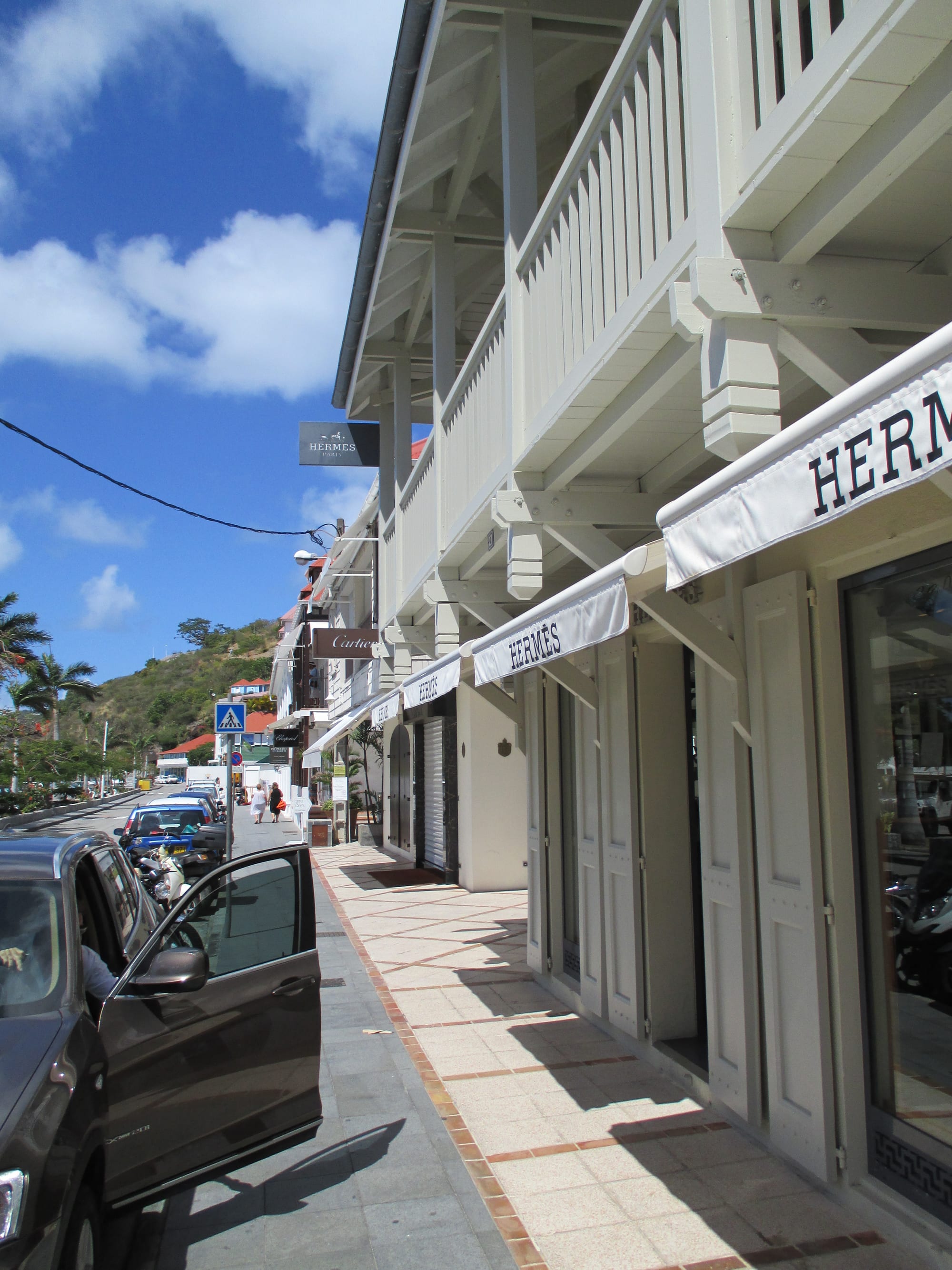 A row of shuttered boutique storefronts for Hermès, Cartier and Chopard along a quiet street in Gustavia