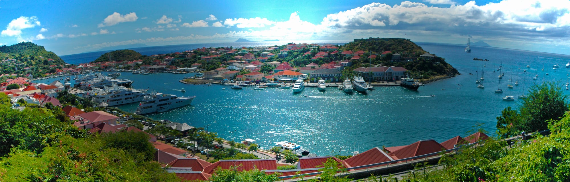 A harbour filled with yachts surrounded by red-roofed buildings on a hillside