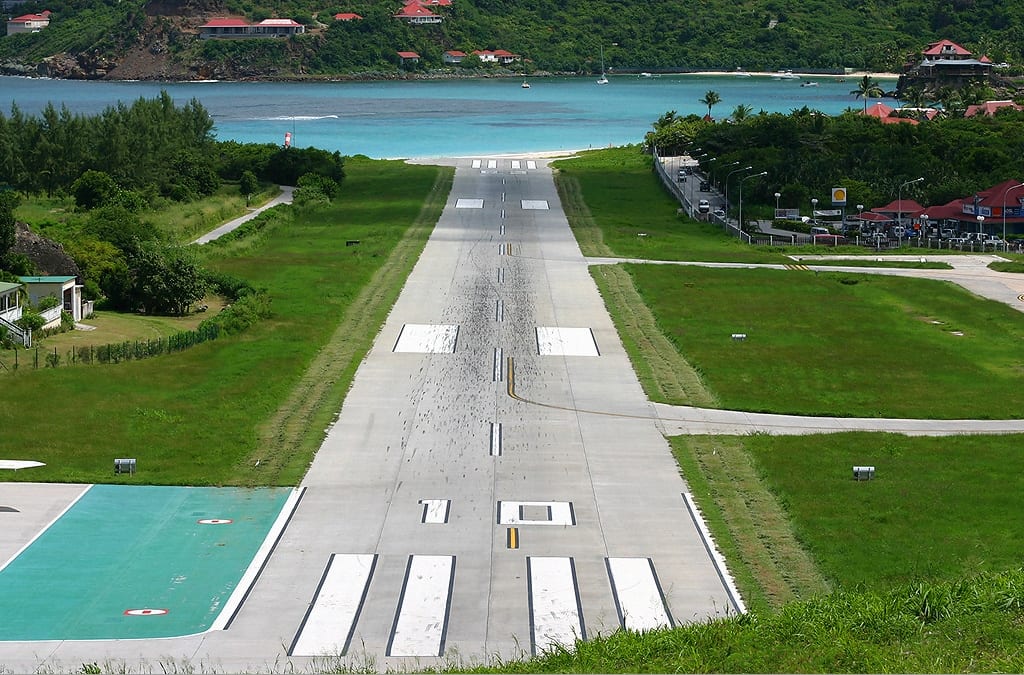 A short airport runway ending abruptly near a beach