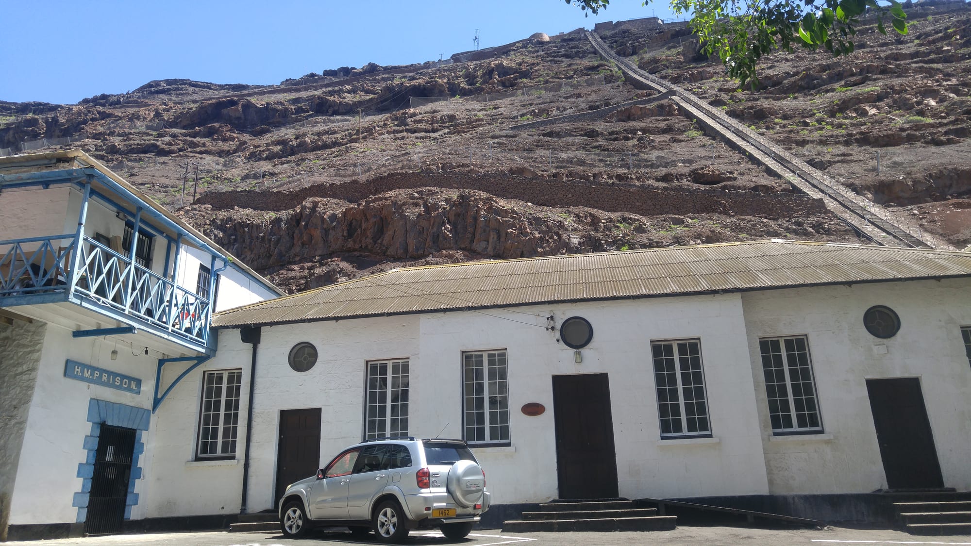A very long, steep straight staircase climbing the bare cliff face directly behind the buildings of Jamestown