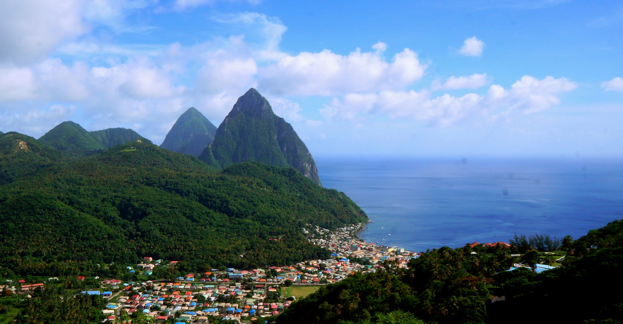 Two steep volcanic peaks rising directly from the sea beside a coastal town