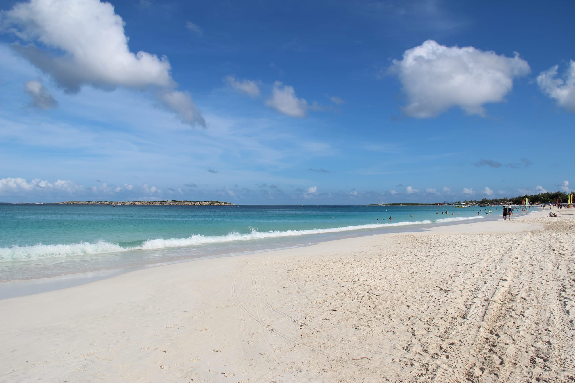 A long curved beach lined with palm trees and beach bars
