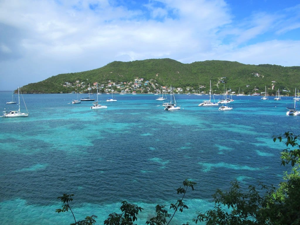 A sheltered bay with sailboats at anchor surrounded by green hills