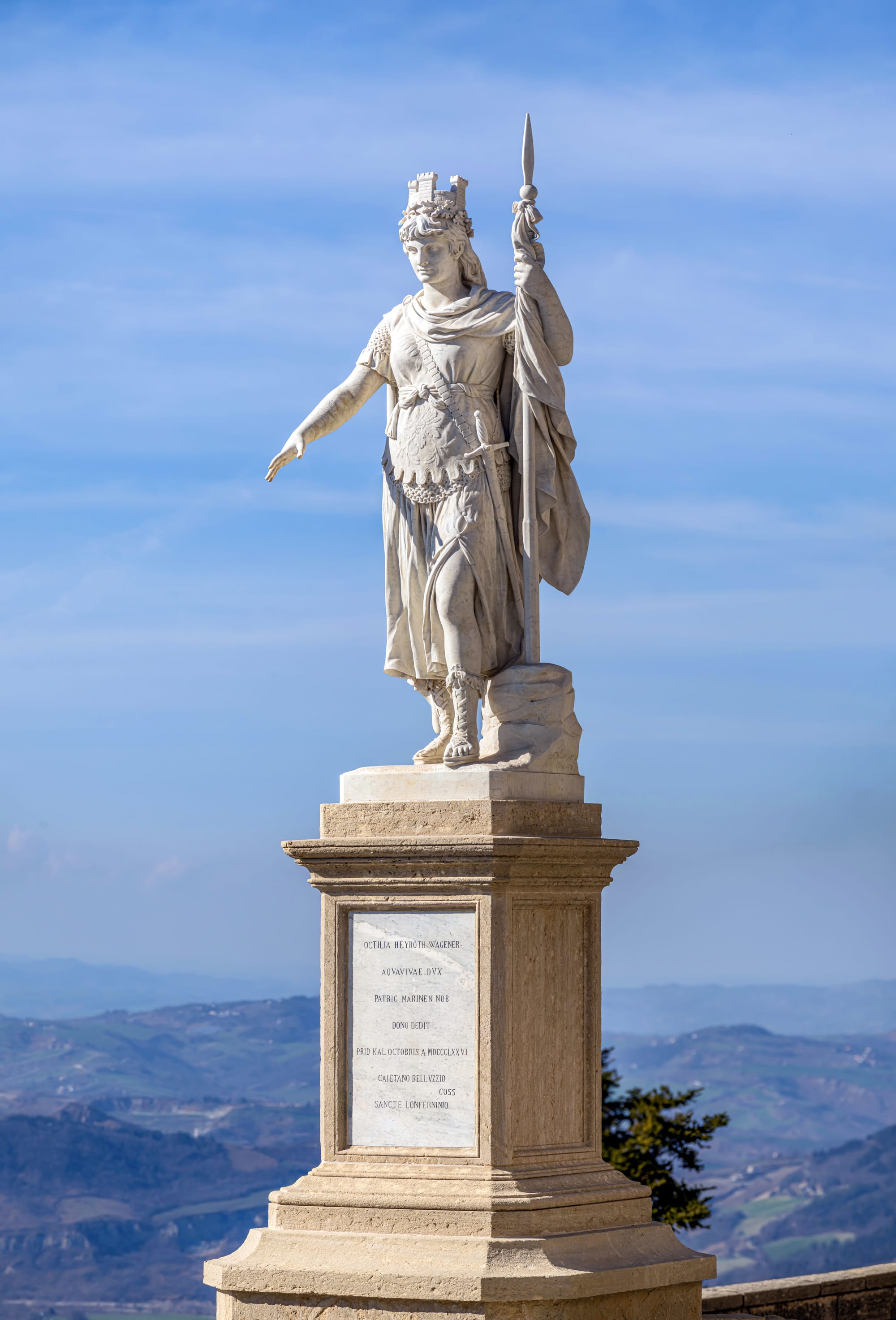 A statue overlooking a view across a wide, hazy plain