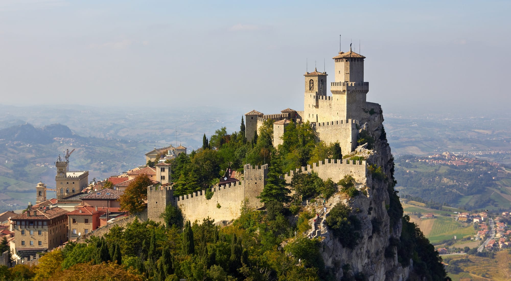 A medieval stone fortress tower perched on a rocky mountain ridge