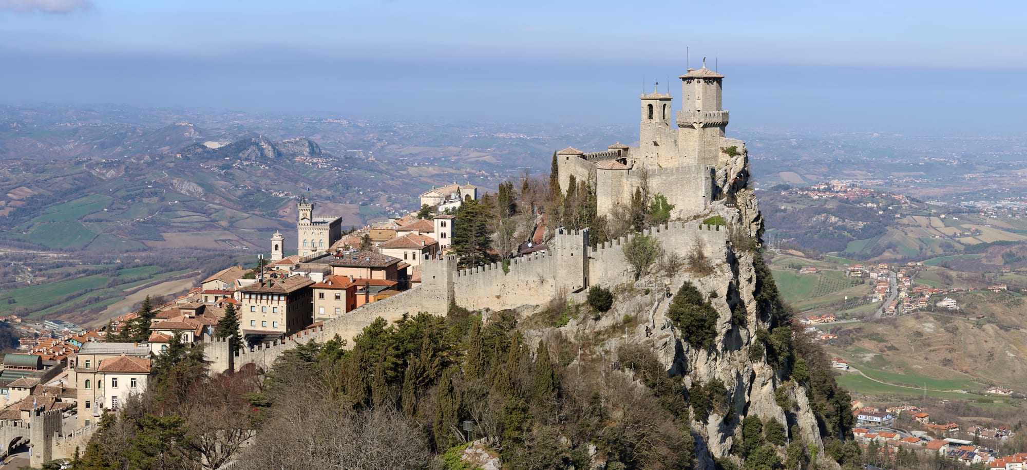 A stone fortress tower on a cliff edge overlooking rolling countryside