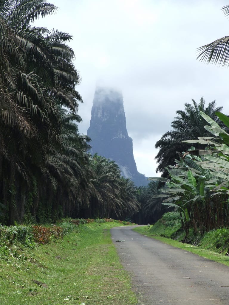 A tall, sheer volcanic spire rising above dense rainforest