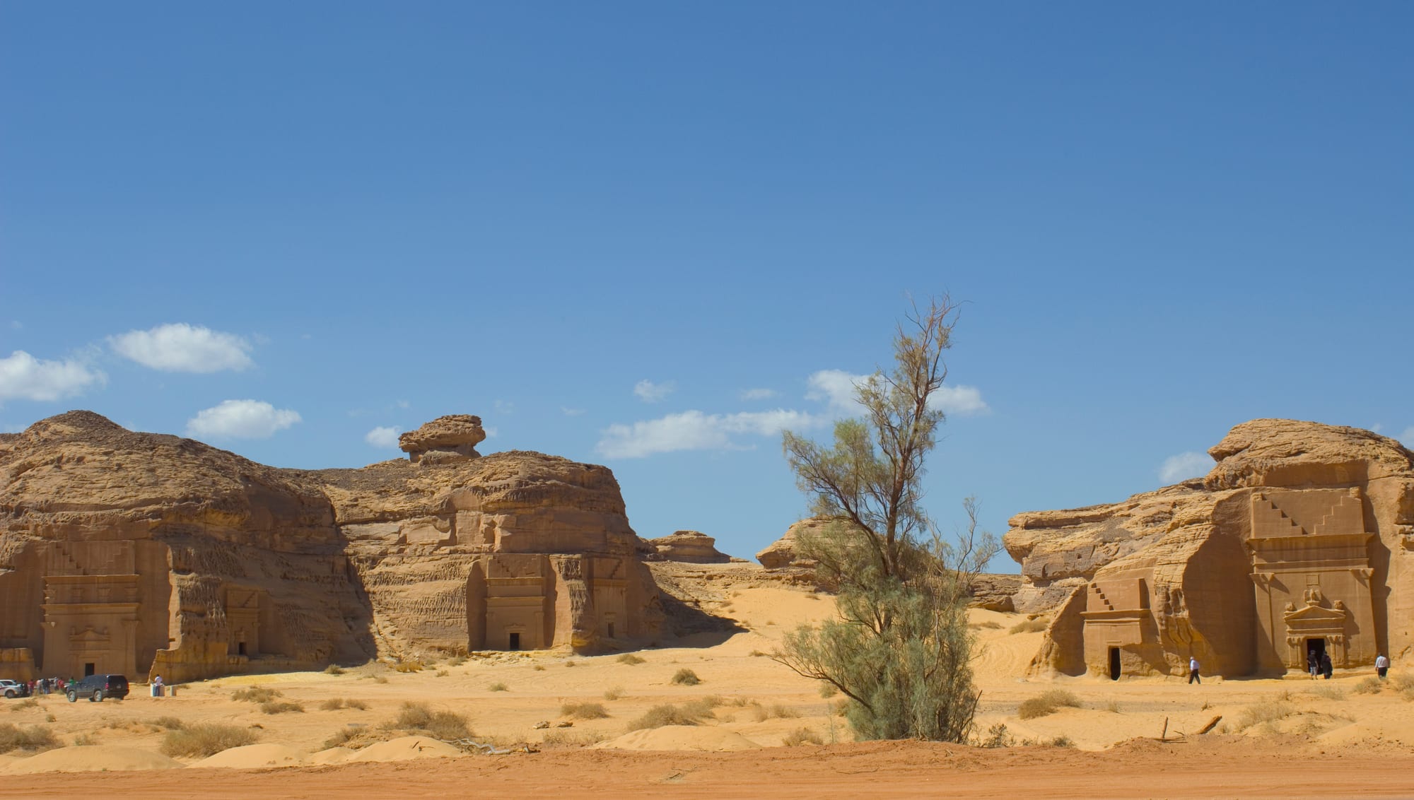 A row of large tomb facades carved into a sandstone rock face