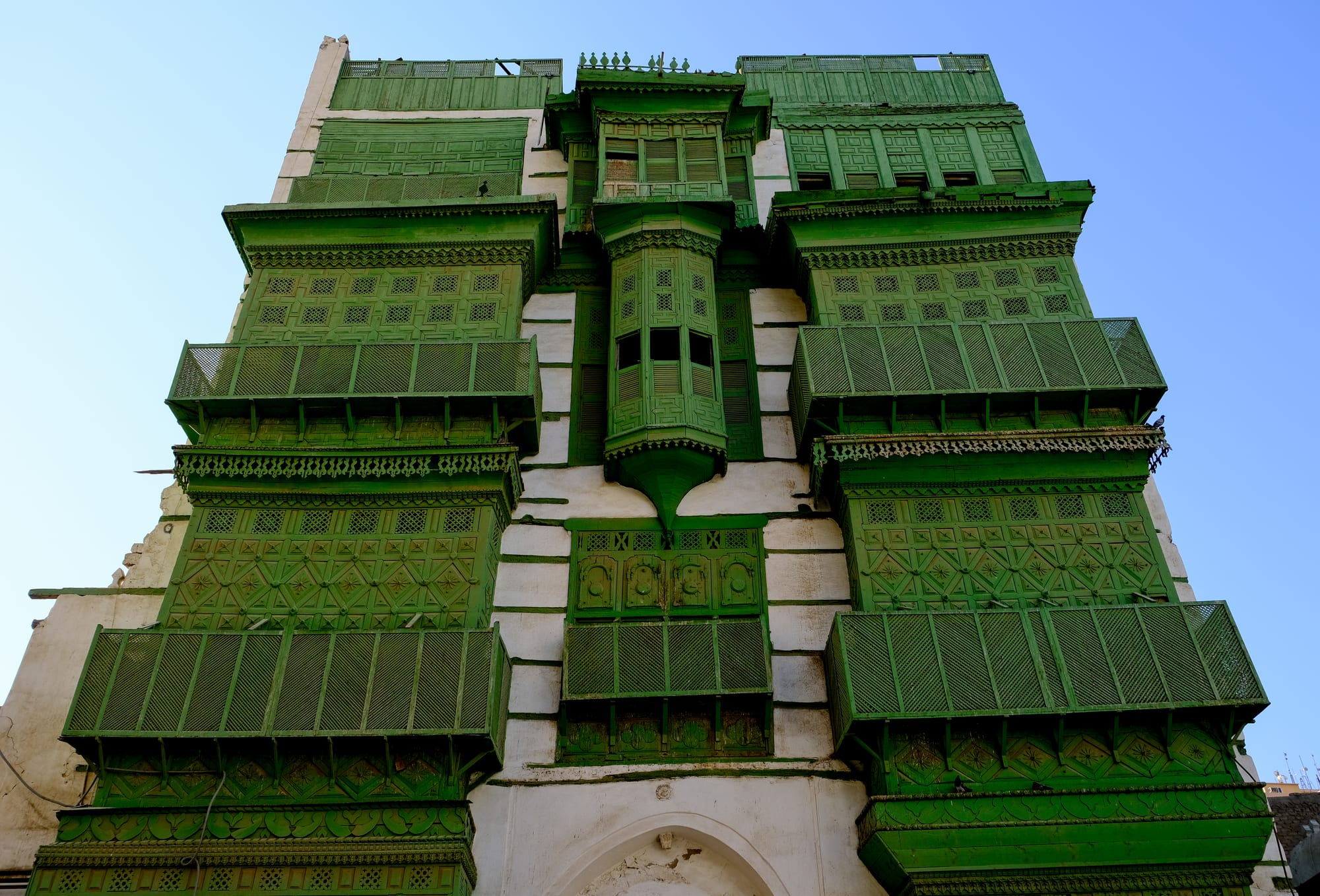 Ornate green carved wooden window shutters on a historic building facade