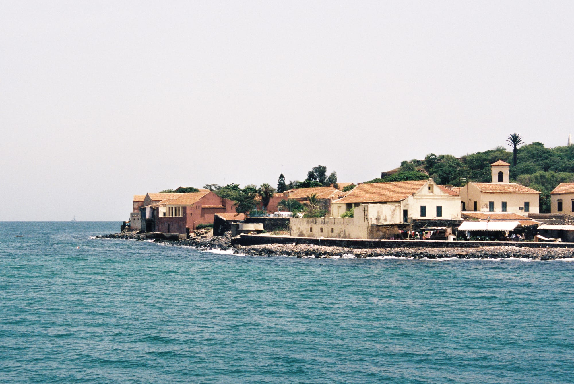 Colourful colonial-era buildings and a fort on the small, low island of Gorée seen from the water