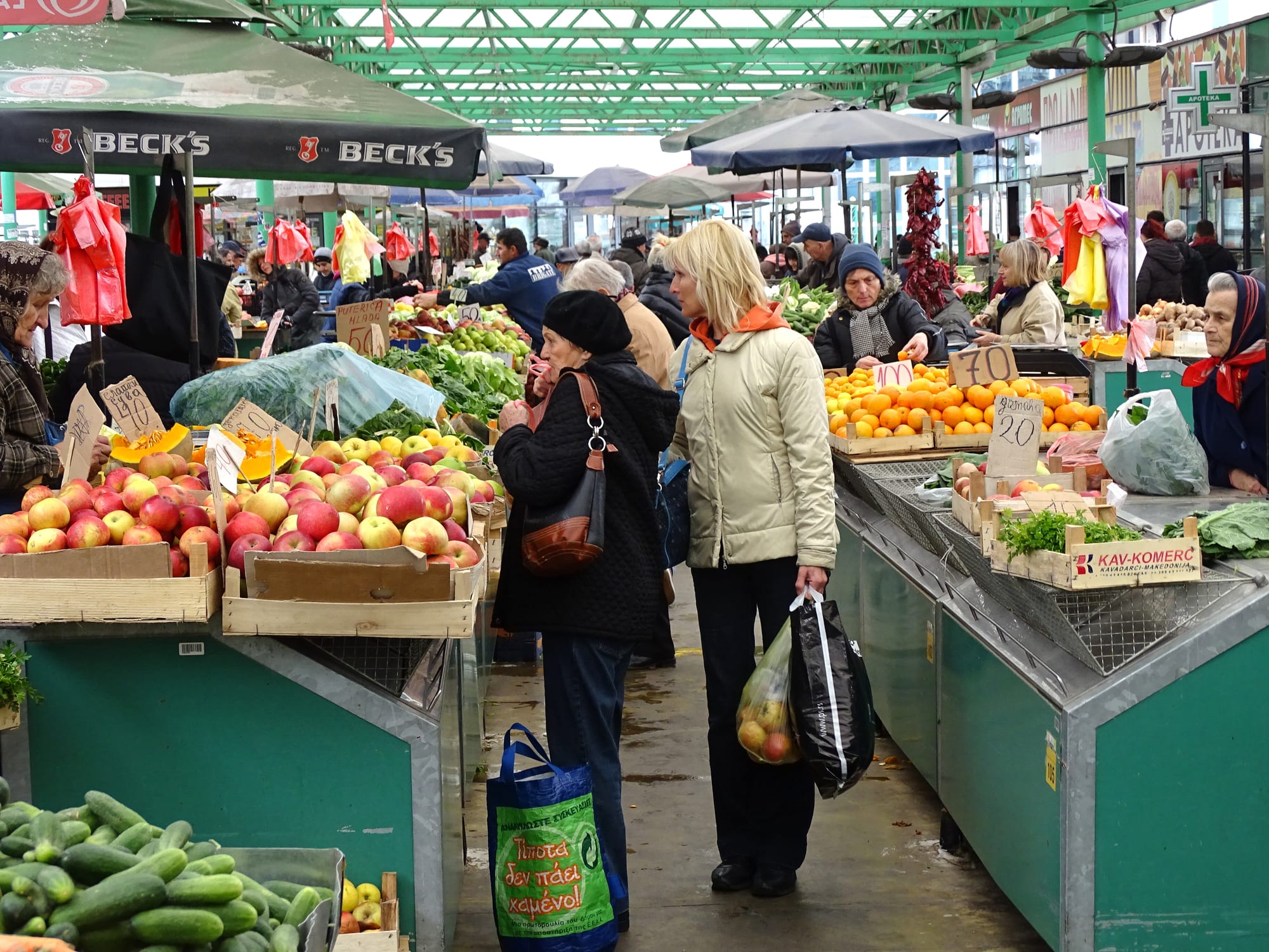 An outdoor produce market with stalls and shoppers