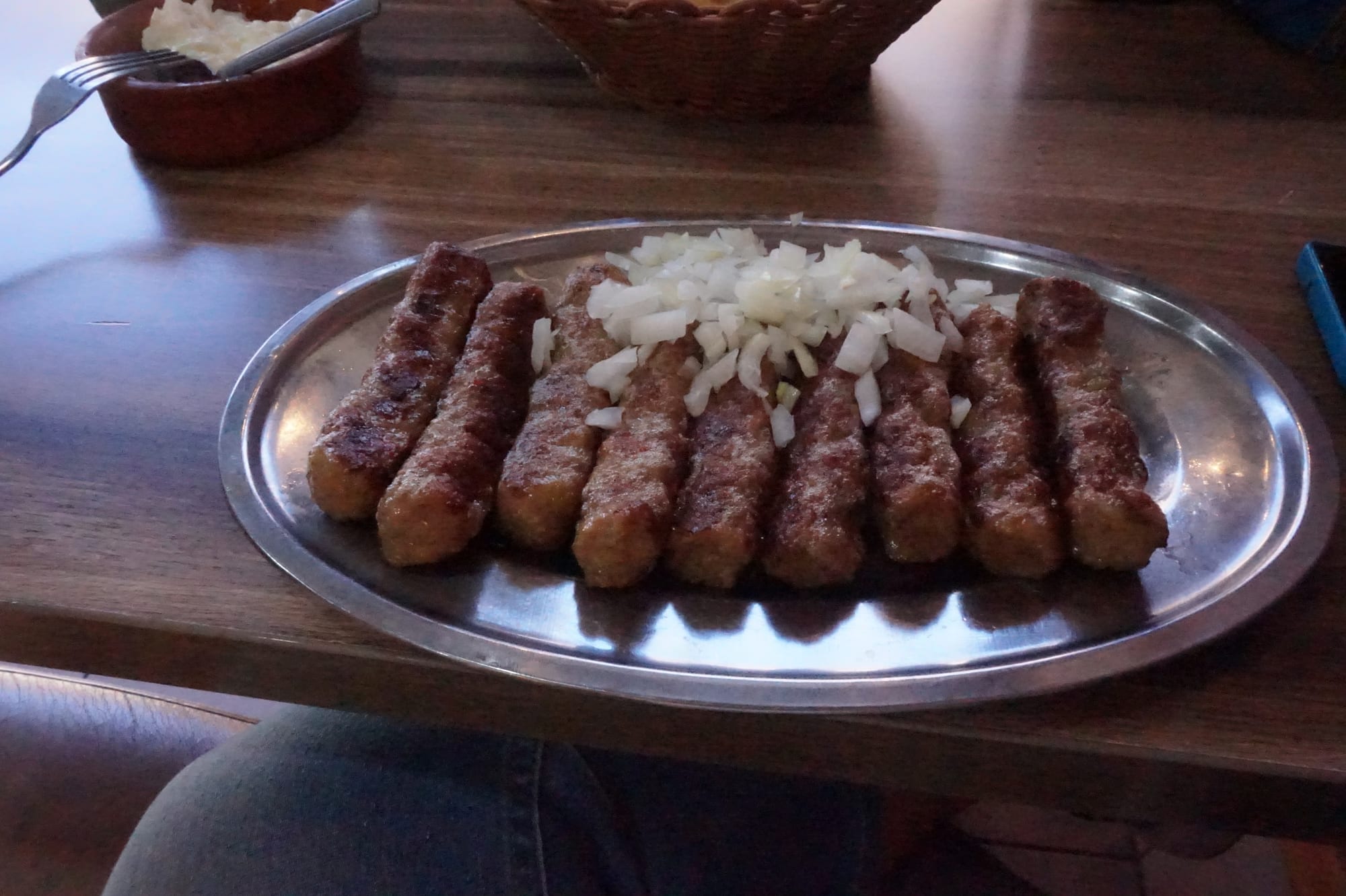 Small grilled meat rolls served with flatbread and onion