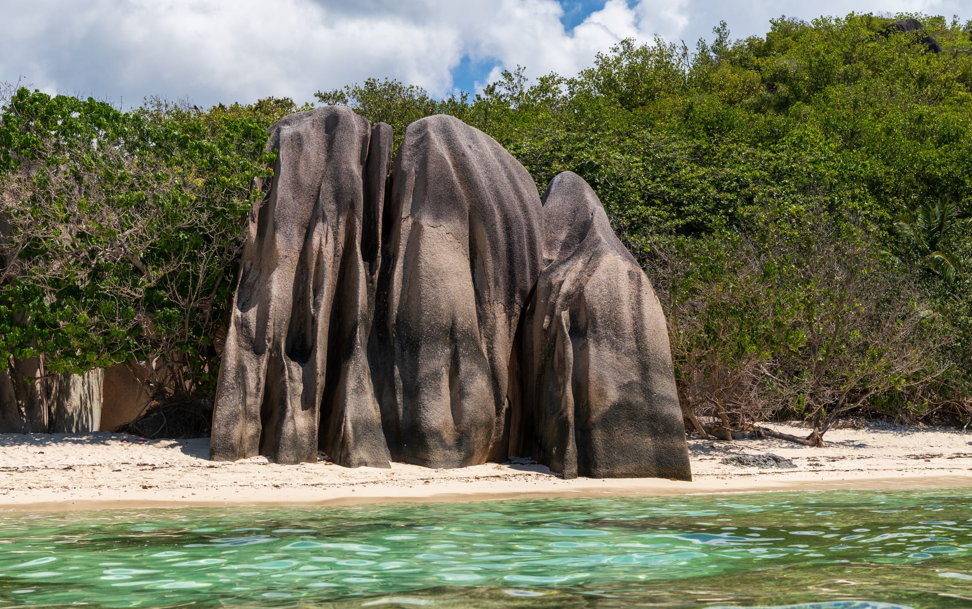 Enormous smooth granite boulders framing a beach with turquoise water