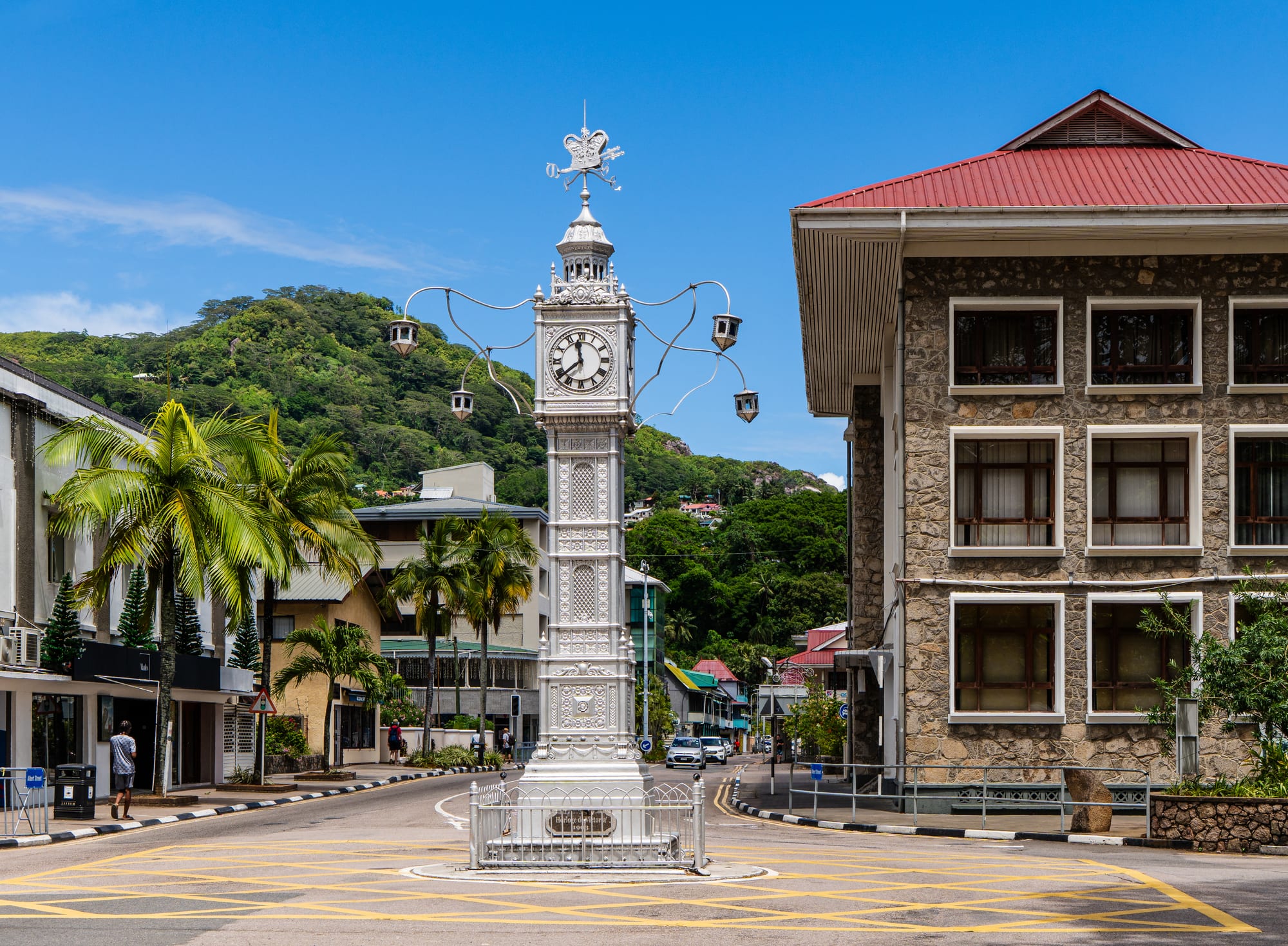A small ornate clock tower at a city intersection