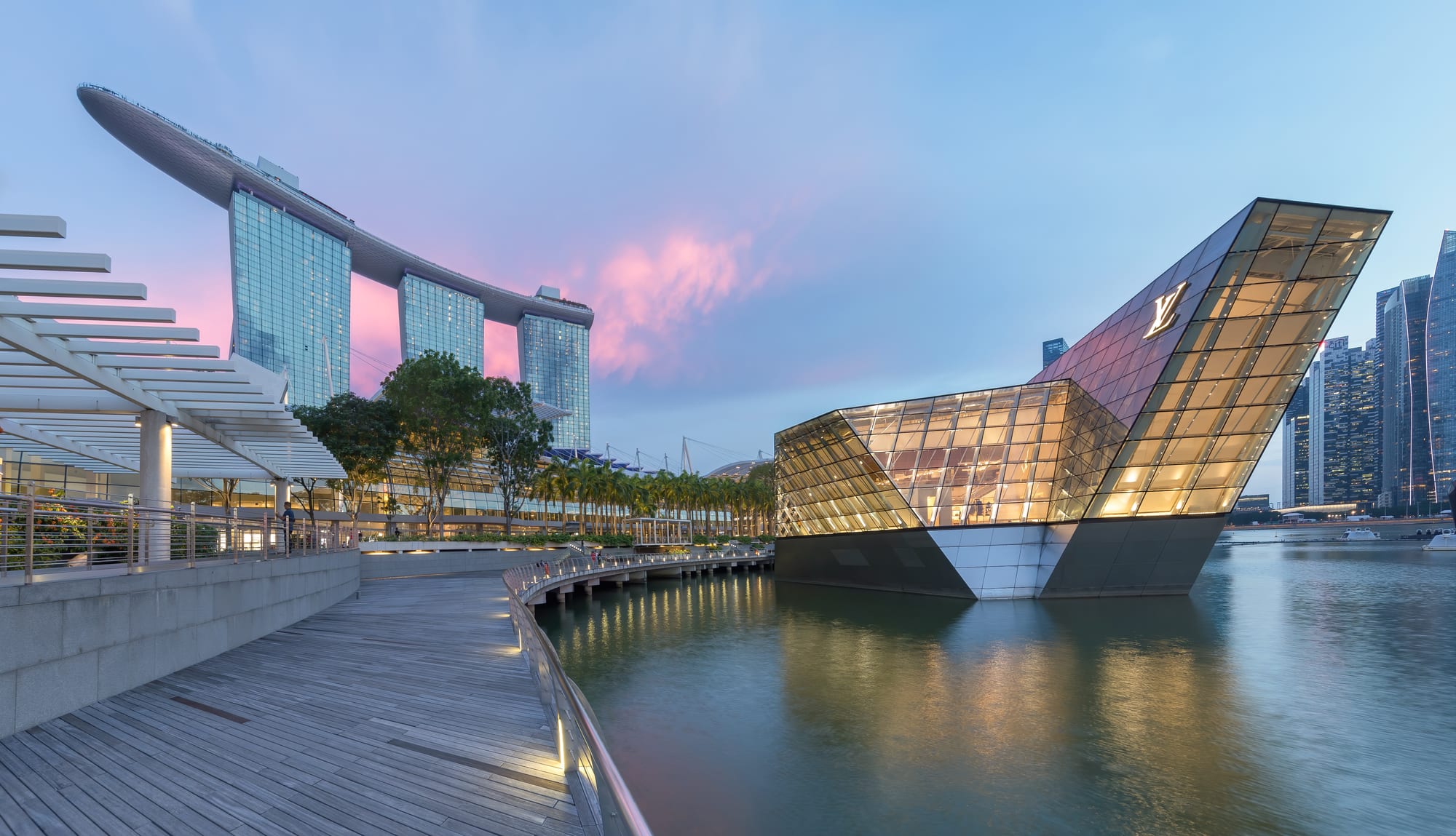 Three tall connected towers topped with a ship-shaped platform, illuminated at dusk