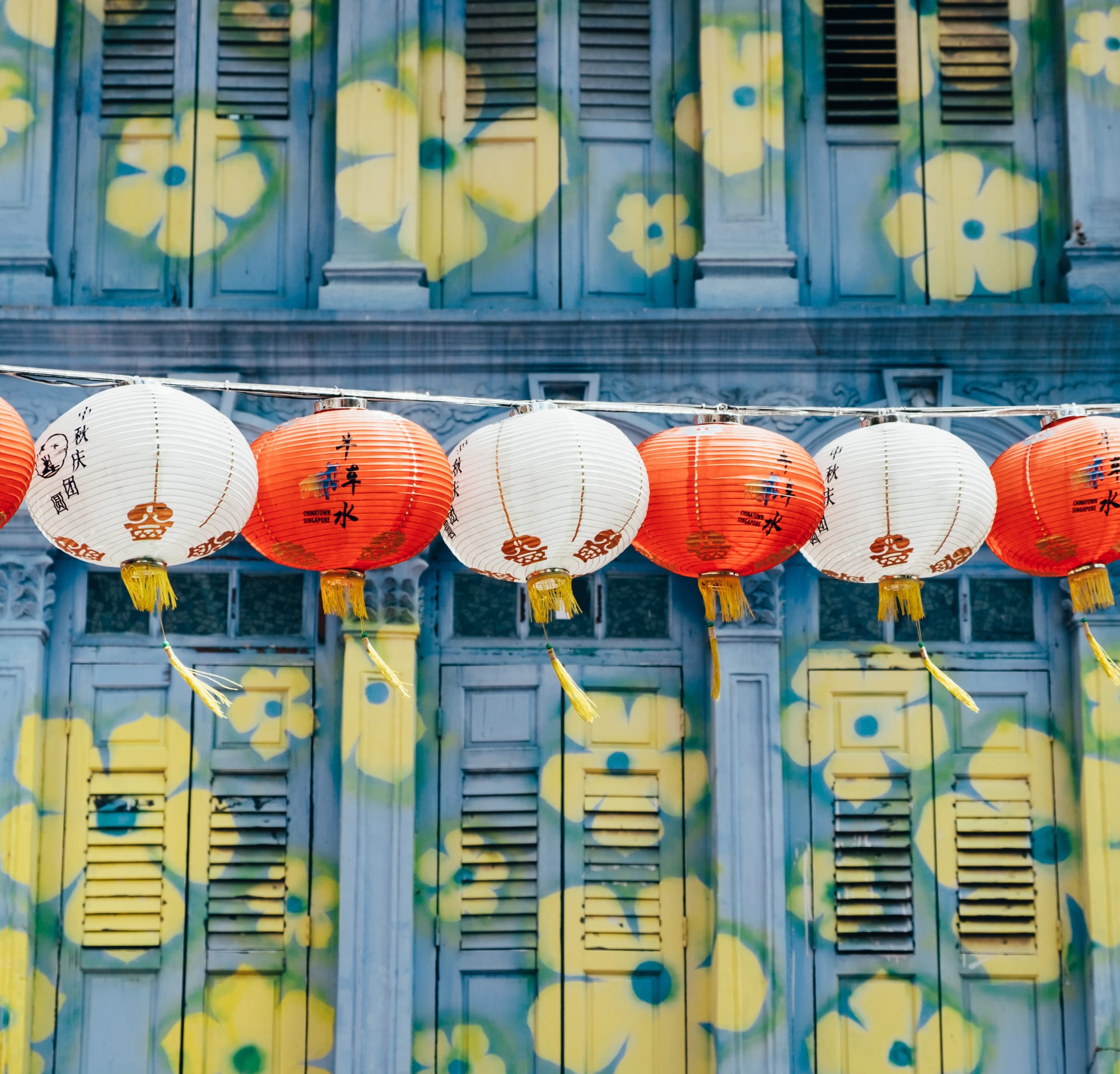 Colourful shophouses lining a street decorated with red lanterns
