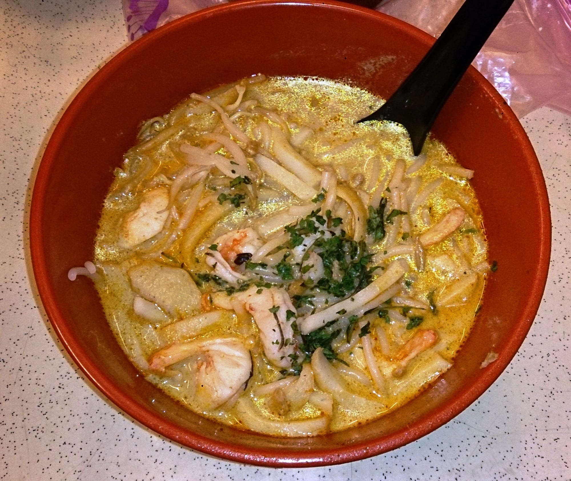 A bowl of noodle soup in a spicy coconut broth