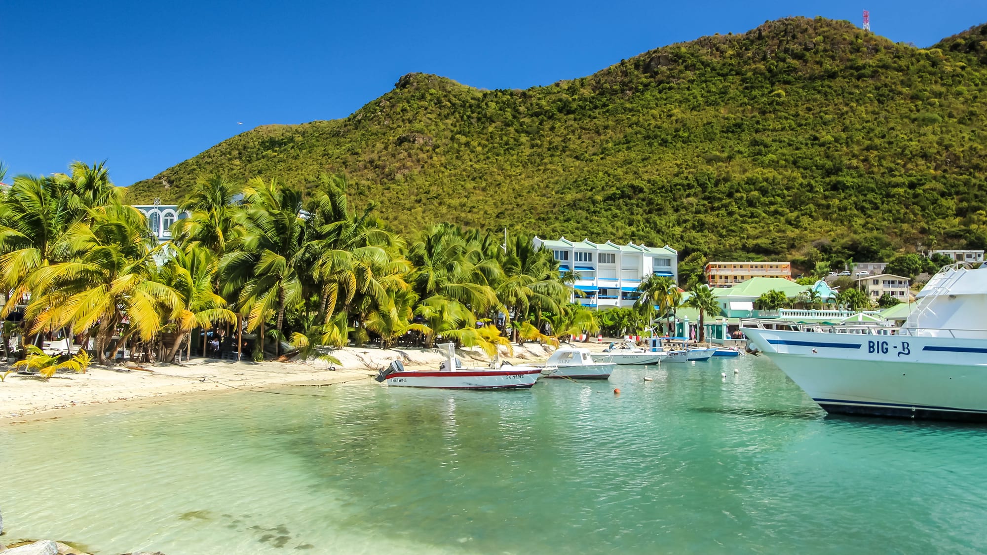 A beach with calm water lined by a row of buildings and a boardwalk