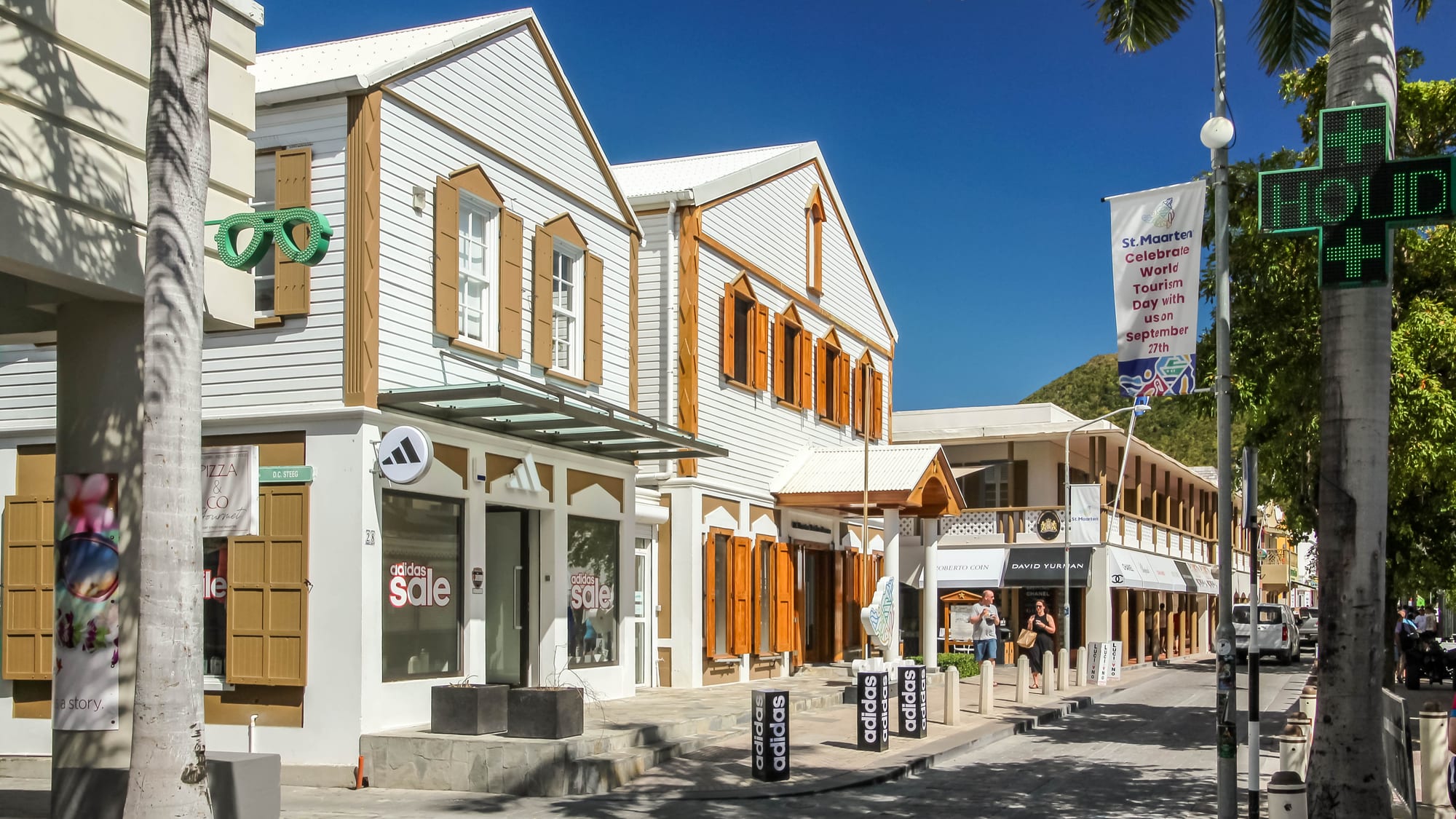 A busy shopping street lined with colourful buildings near a cruise port