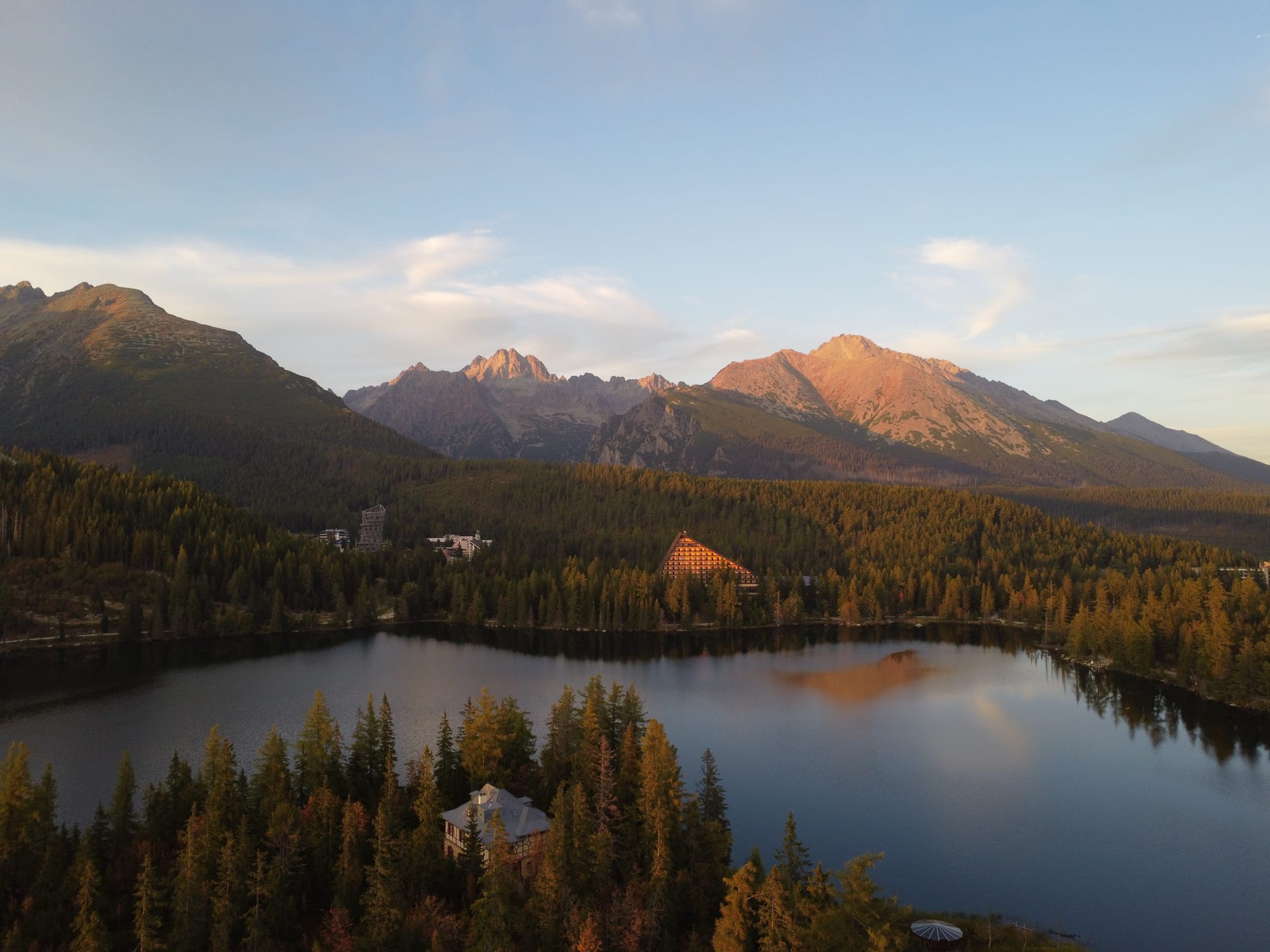 Jagged snow-capped mountain peaks reflected in a glacial lake at sunset