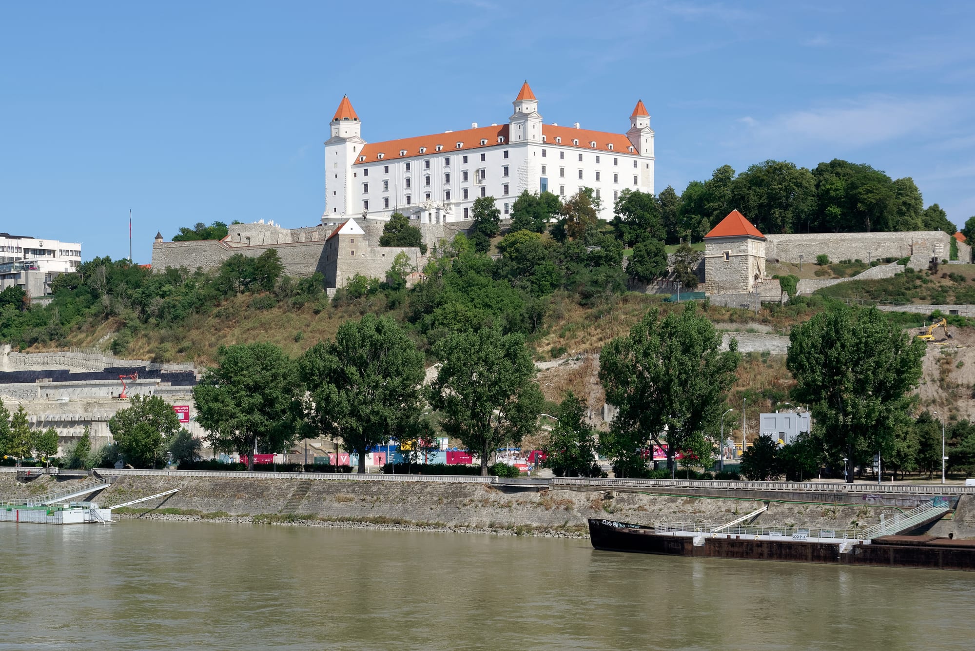 A large white castle with corner towers overlooking a city and river