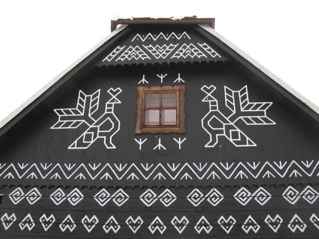 A wooden house painted with intricate white geometric patterns