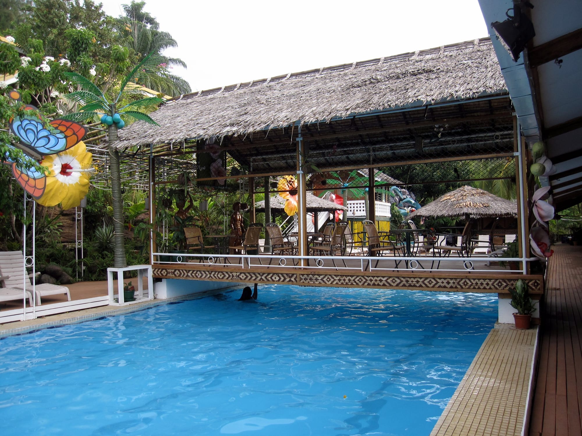 A modest tropical hotel building surrounded by palm trees