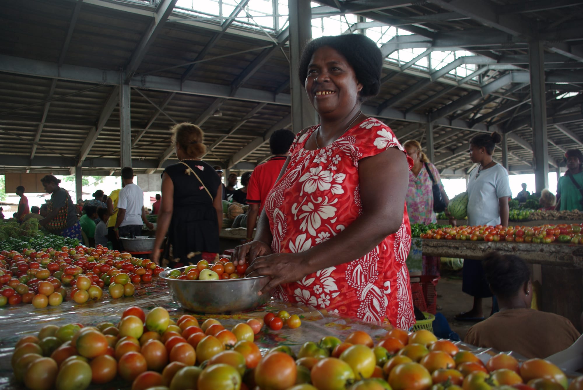 A woman selling tomatoes at an outdoor market
