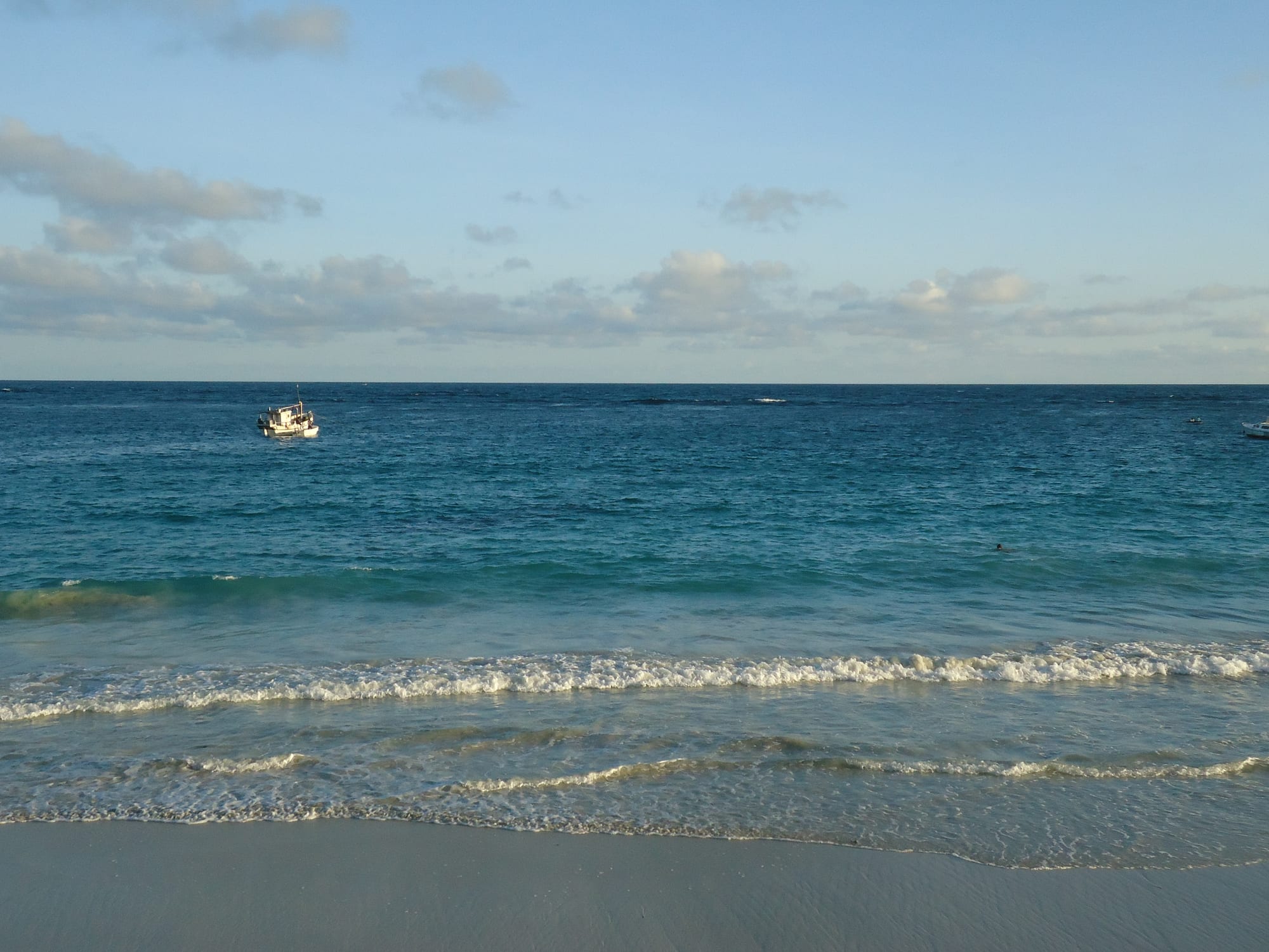 A wide white sand beach along a calm turquoise coastline