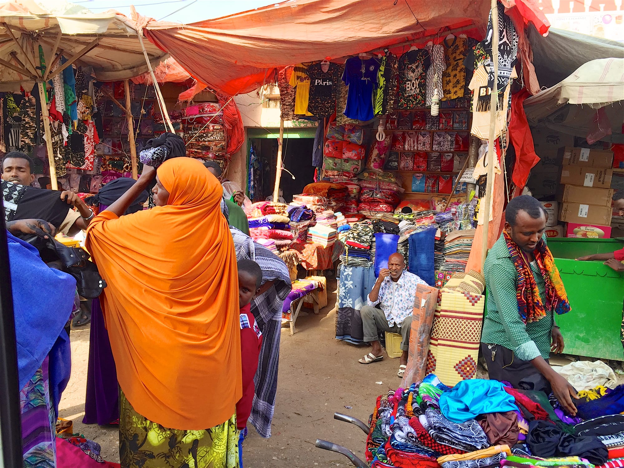 A busy outdoor street market with vendors and goods for sale