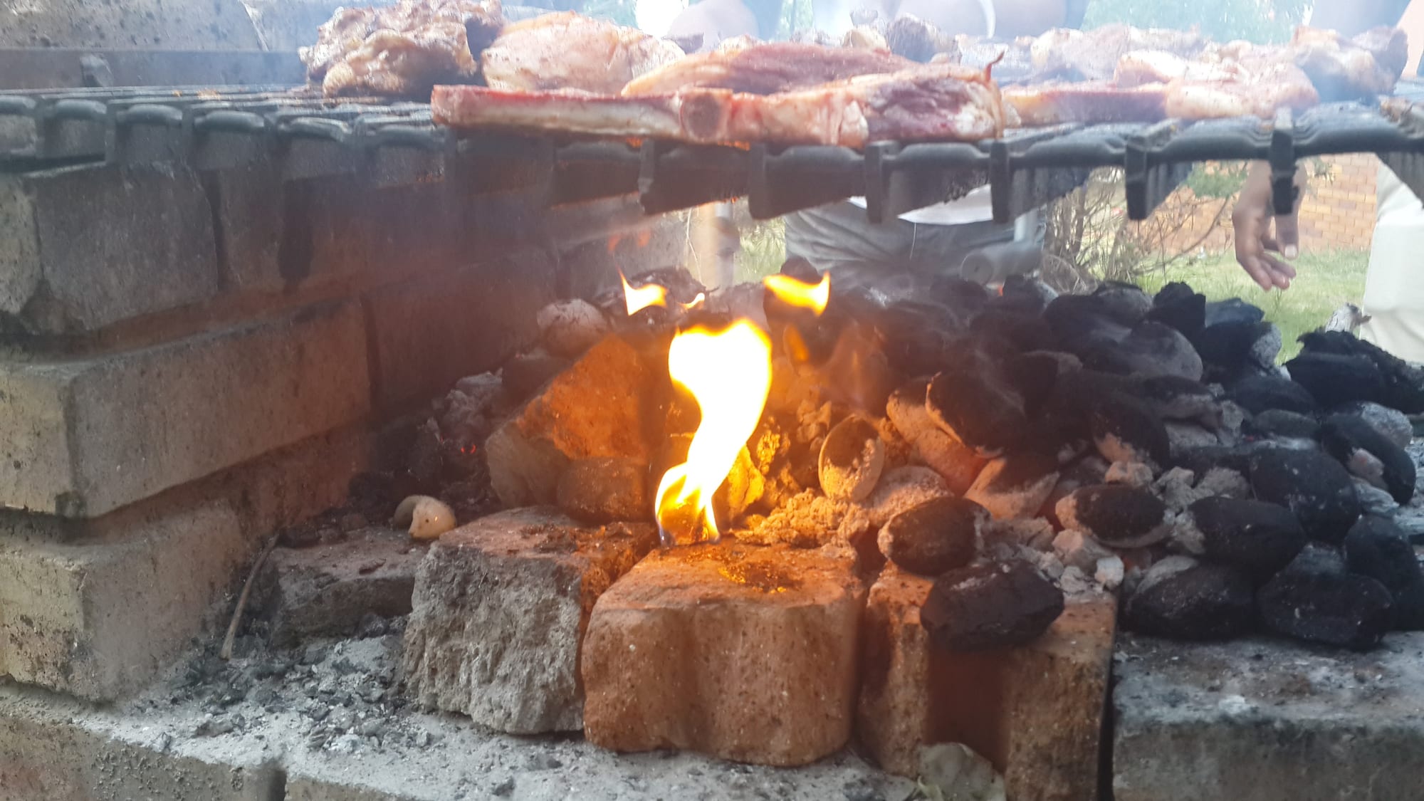 Meat grilling on a rack over an open coal fire