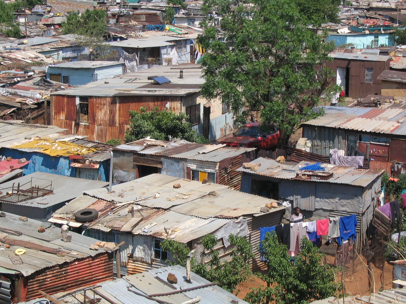 An aerial view of a densely packed township of corrugated-iron roofed homes with laundry hanging between them