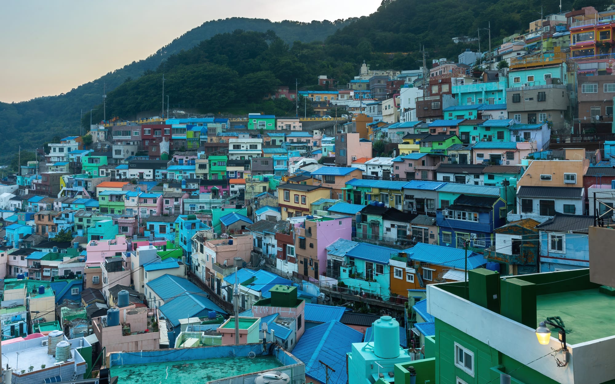 A hillside neighbourhood of brightly coloured houses stacked above a harbour