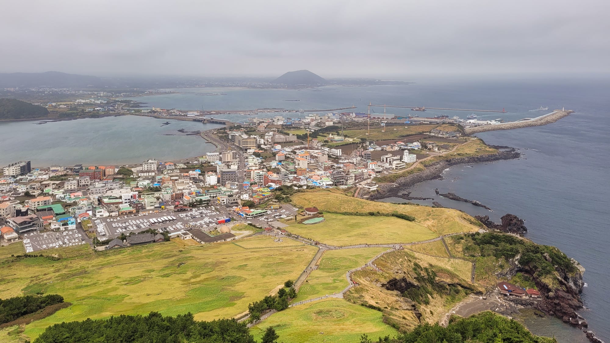 A dramatic volcanic crater rising above the sea beside a coastal town