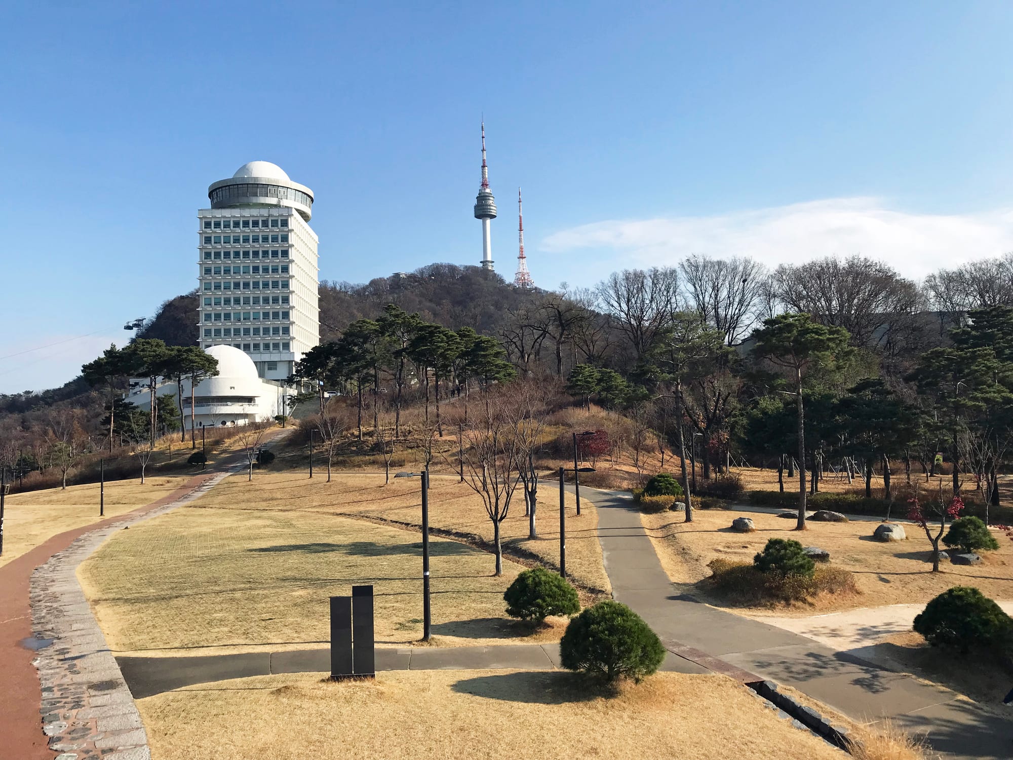 A tall communications tower rising above a hilltop park in a city