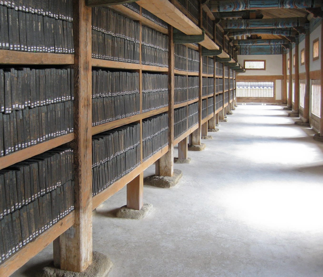 Long wooden shelves of ancient printing blocks lining a temple storage hall