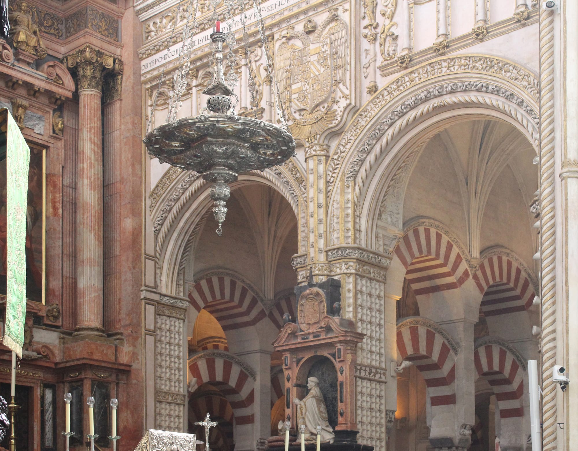 A forest of red-and-white striped double arches inside a vast mosque interior