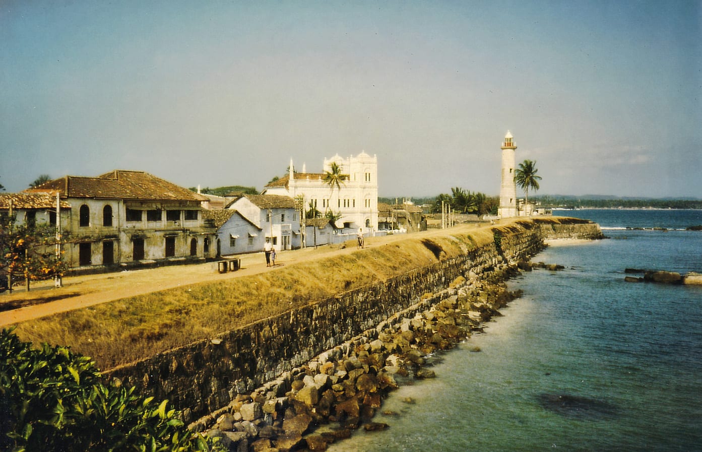 Old colonial-era fortification walls and buildings along a coastline