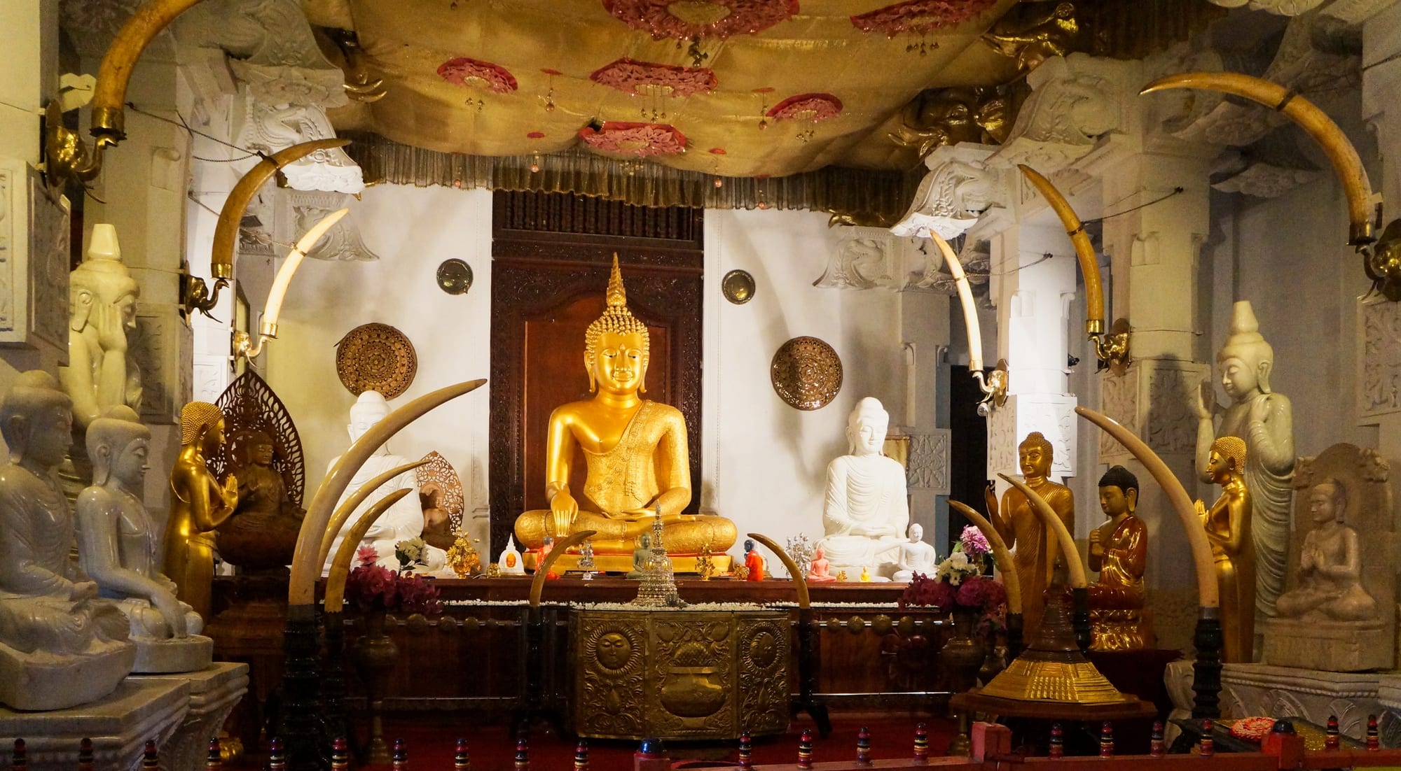 Rows of seated golden Buddha statues inside the Temple of the Sacred Tooth Relic in Kandy