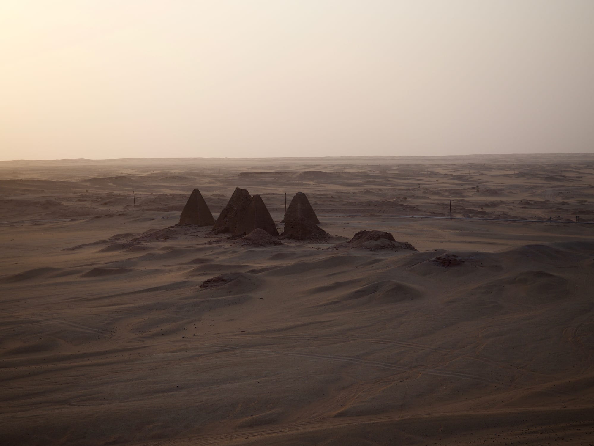 Small pyramids silhouetted at dusk beneath a flat-topped sacred mountain