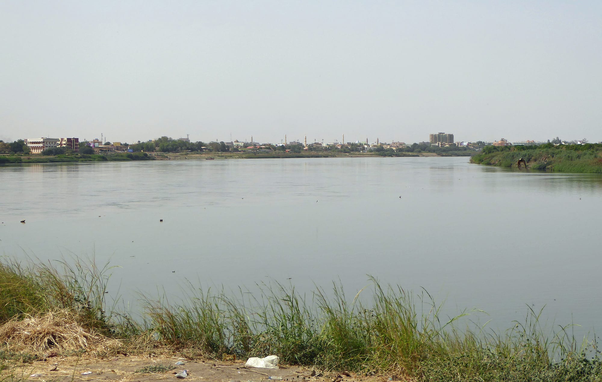 A wide river with a city skyline of minarets and buildings along its bank